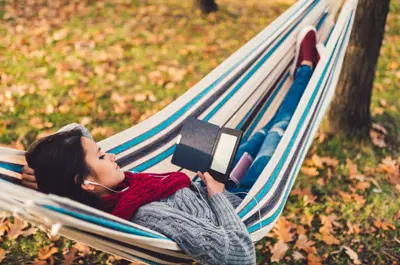 Woman Reading Ebook Outside In A Hammock
