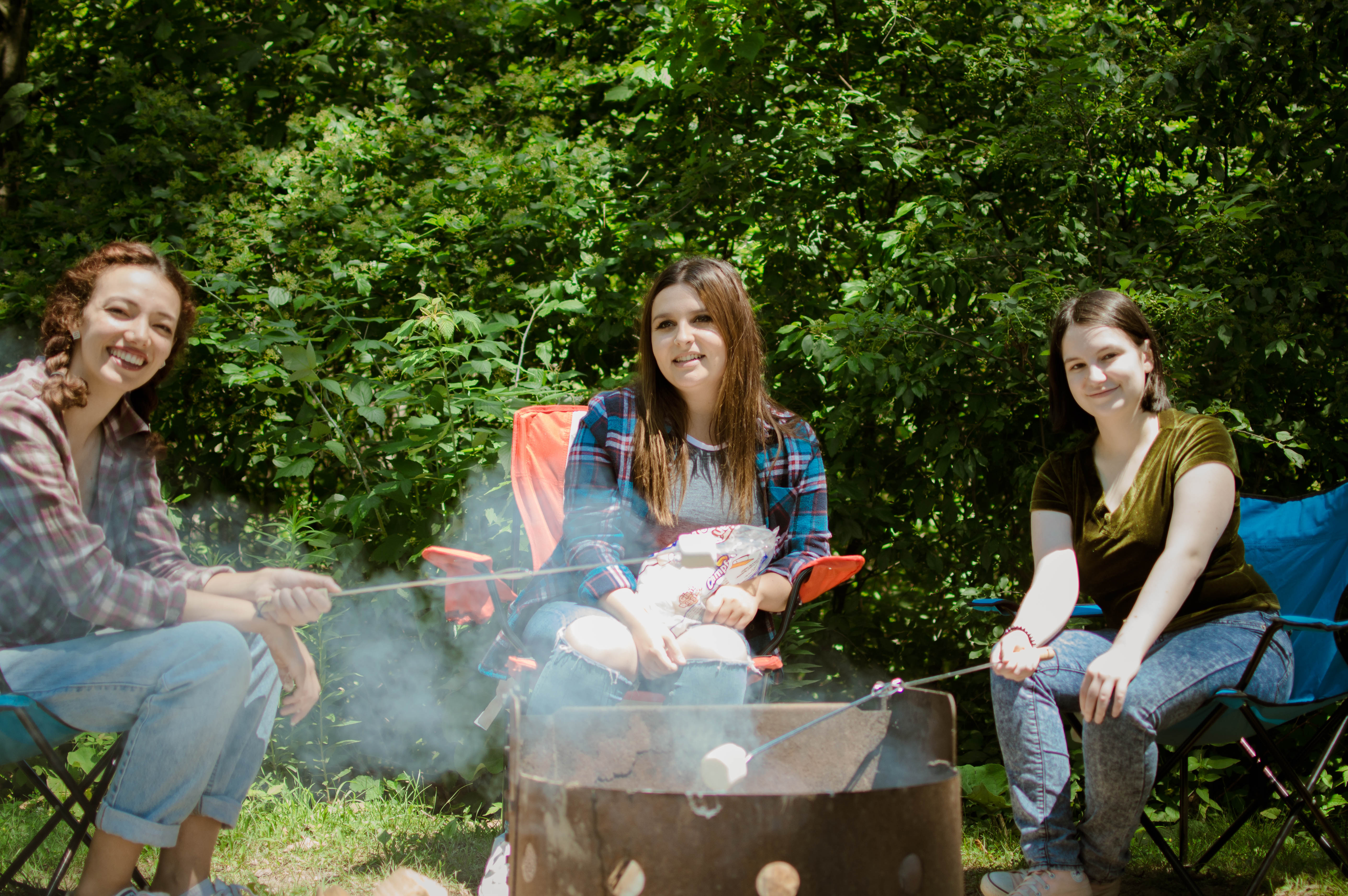 Young women sit around a campfire roasting marshmallows
