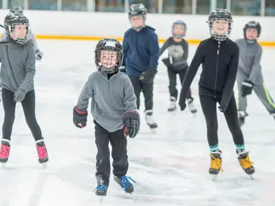 group of children on the ice in hockey helmets