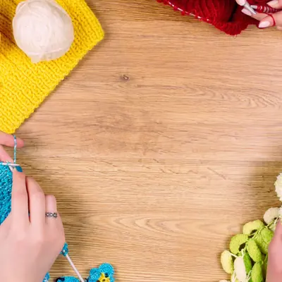 Group knitting at a table with only hands showing