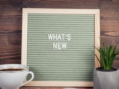 Letter board that says "What's New" beside a cup of coffee