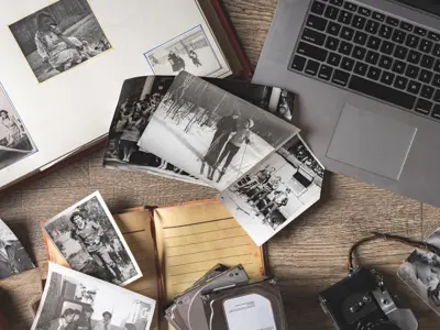 Table covered in old family pictures near a laptop