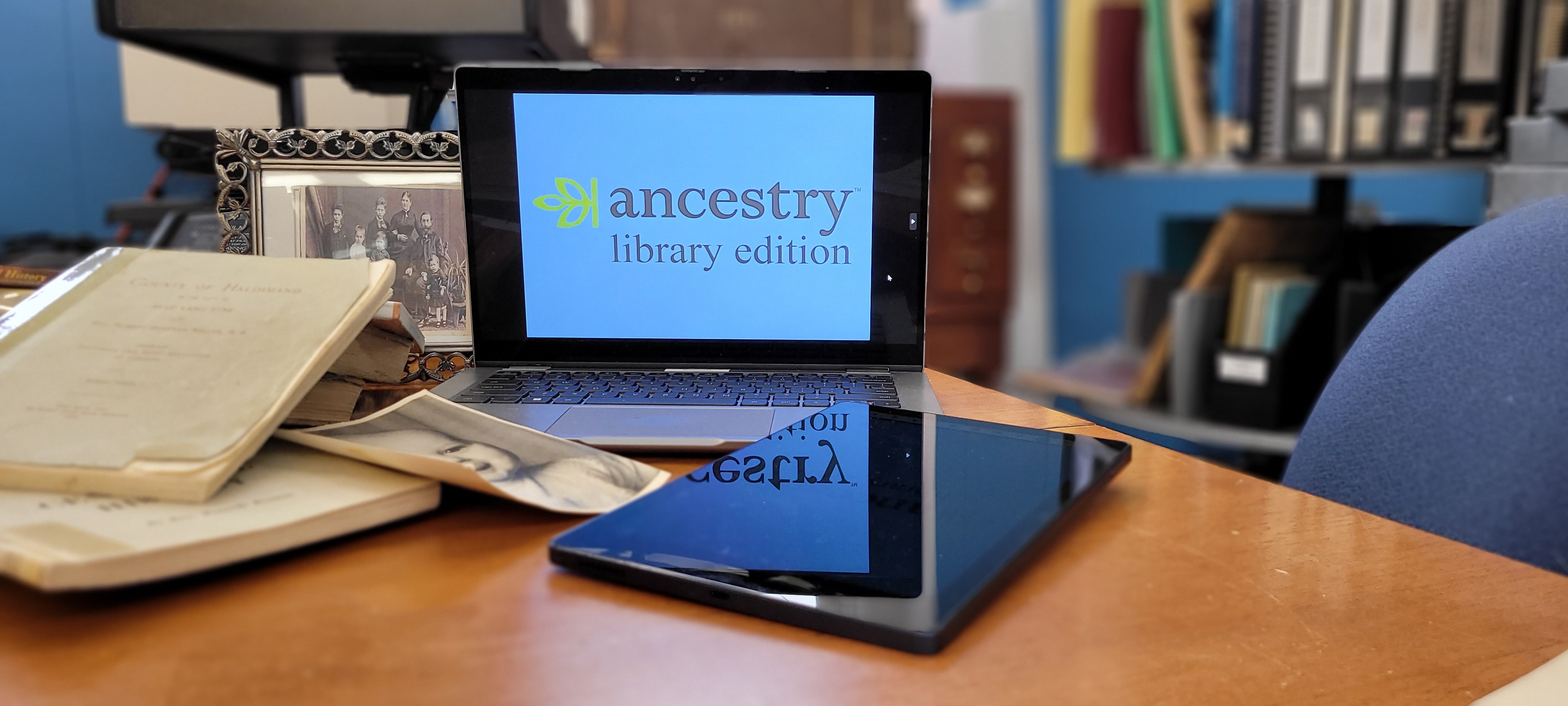 laptop and tablet with local history books and old photo