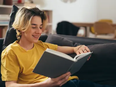 Teen boy reading a book on the couch